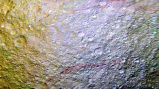На поверхности спутника Сатурна Тефии ученые увидели необычные арочные следы кроваво-красного цвета